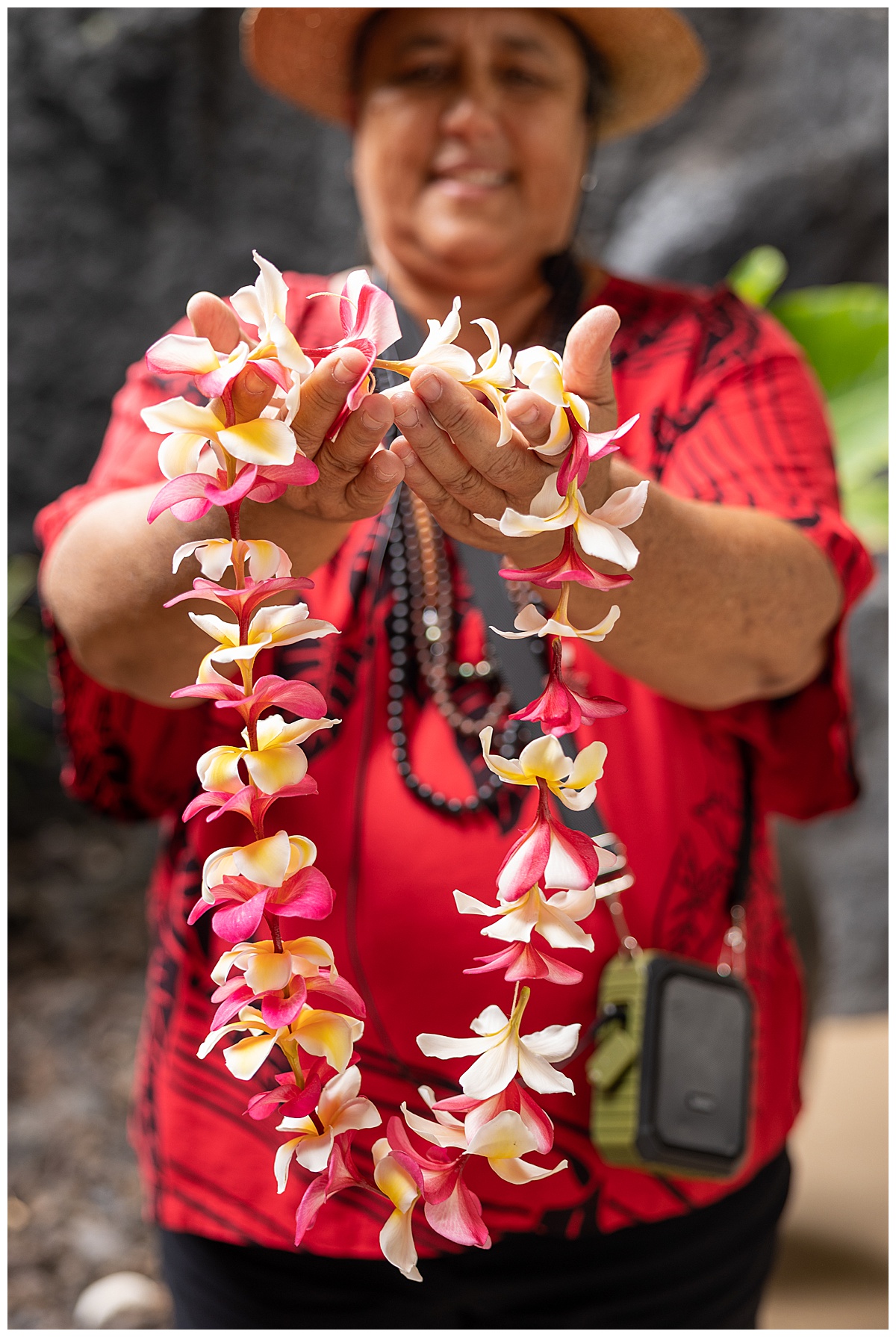 A lei making cultural activity at the Outrigger Kona Resort & Spa. Close up of the teacher holding up the completed lei. The lei flowers are yellow and white flowers with hints of white.
